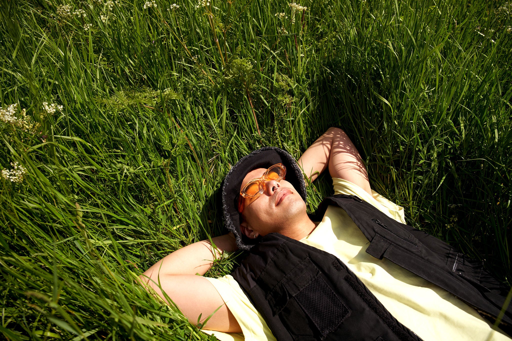 Mann mit Sonnenbrille liegt in einer Wiese