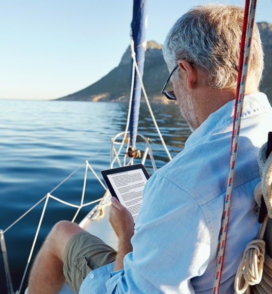 Man reading on his tablet on a sailboat