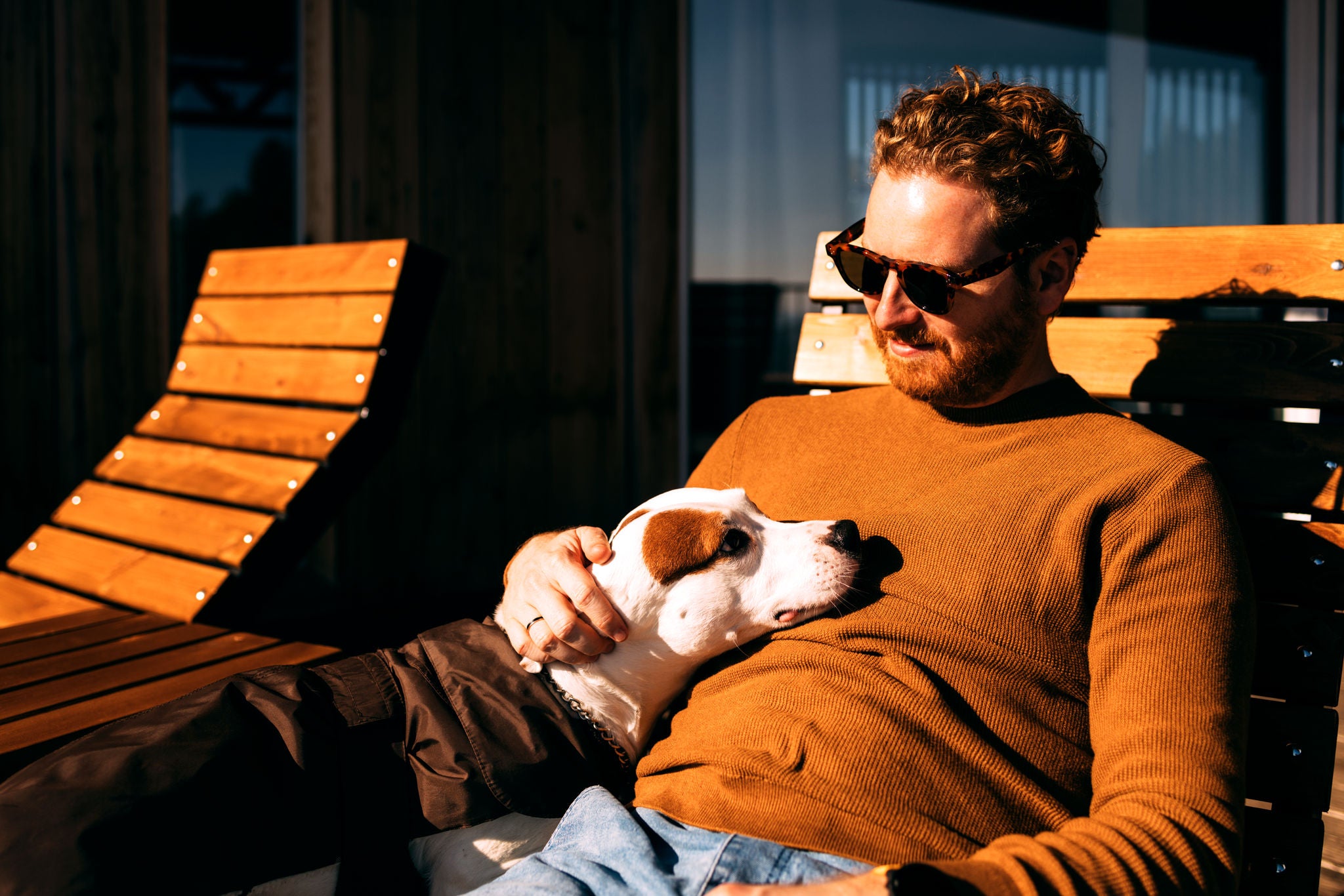 Mann sitzt mit Hund in der Sonne