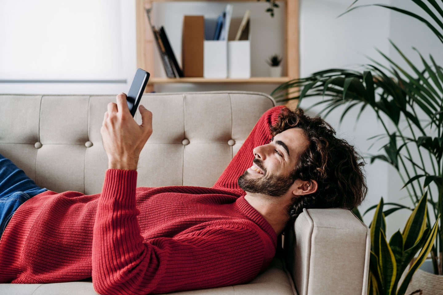 Hombre tumbado en el sofá con móvil en la mano