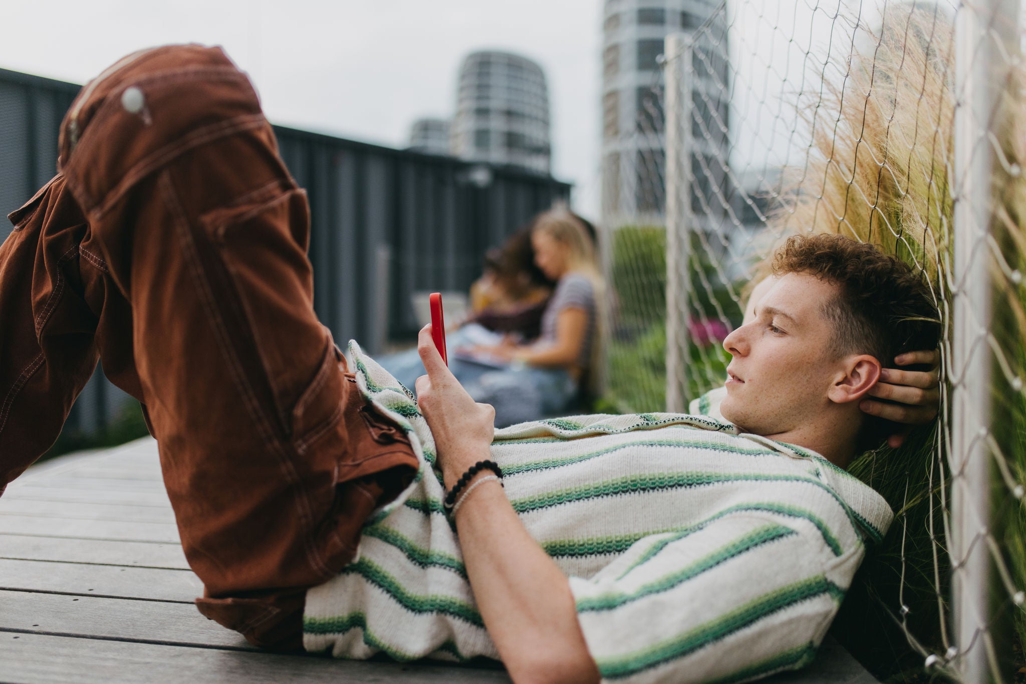 Junger Mann nutzt sein Smartphone unterwegs in der Stadt