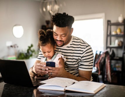 man with baby on his lap checking cell phone