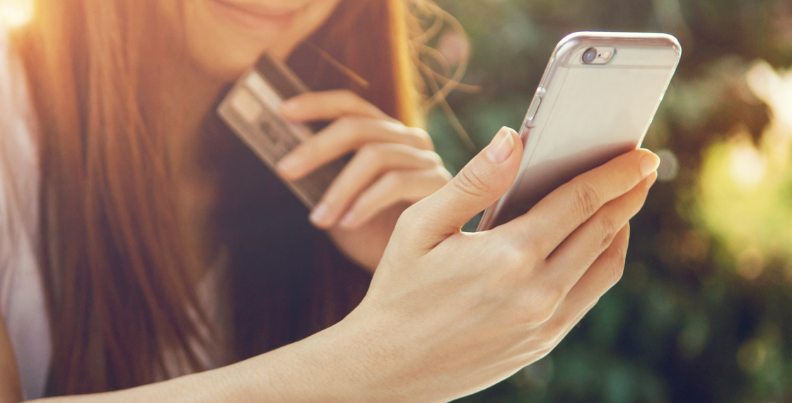 Mujer con tarjeta de crédito y un teléfono en la mano