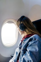 Mujer con cascos mirando por la ventana de un avión