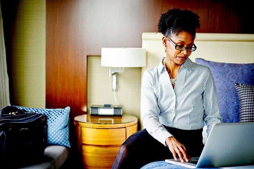 woman sitting on bed with laptop