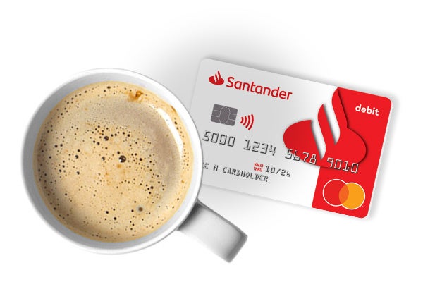 A cup of coffee on a table with a Santander bank debit card