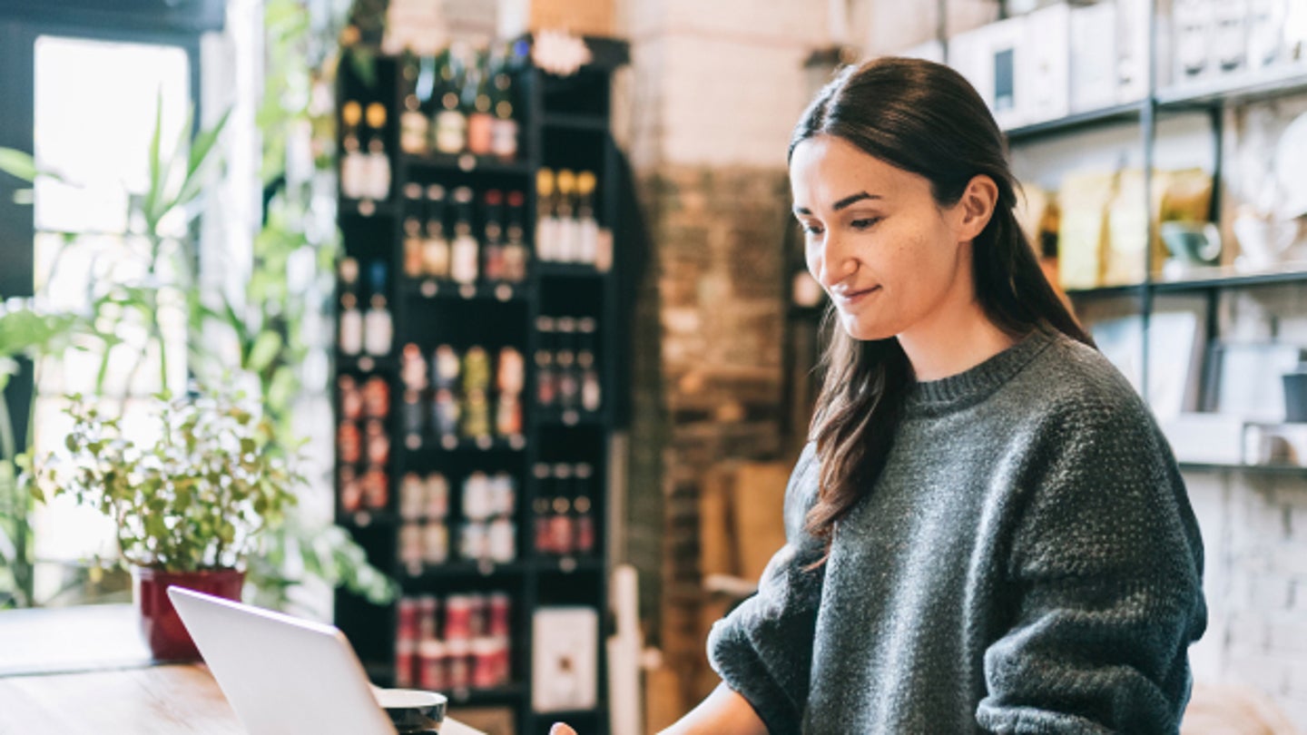 Woman at store counter working on laptop