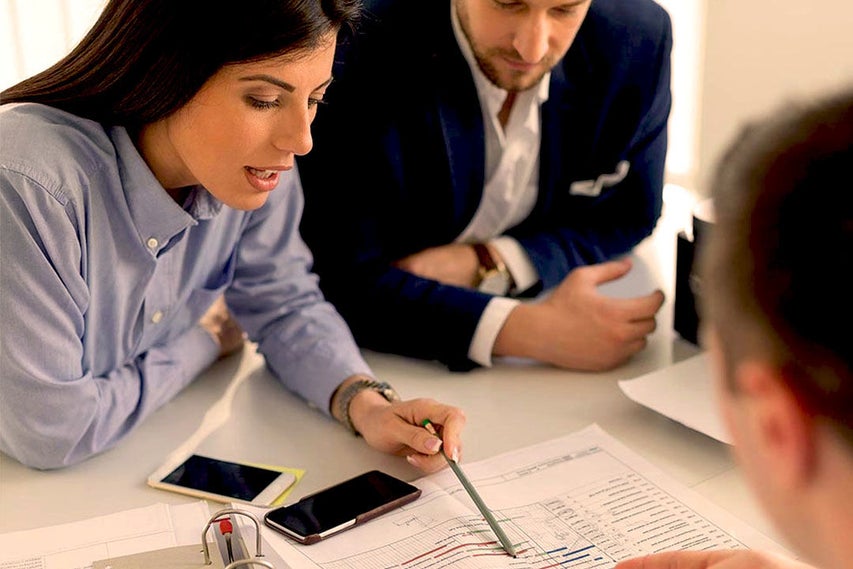 Three people meeting going over paperwork